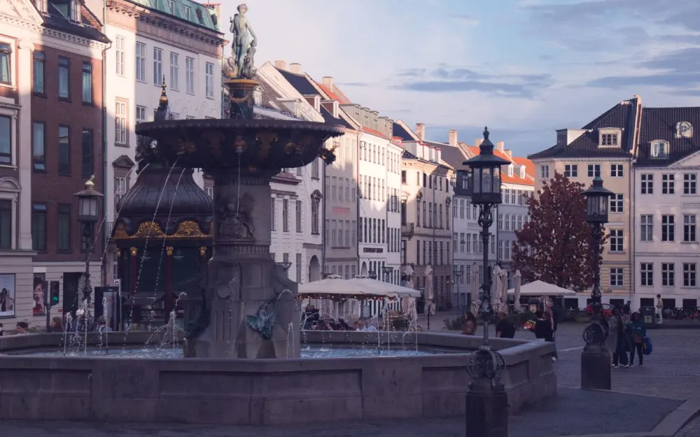 Symbolbild: A beautiful fountain in a historic square of Copenhagen, Denmark, bathed in warm sunlight.