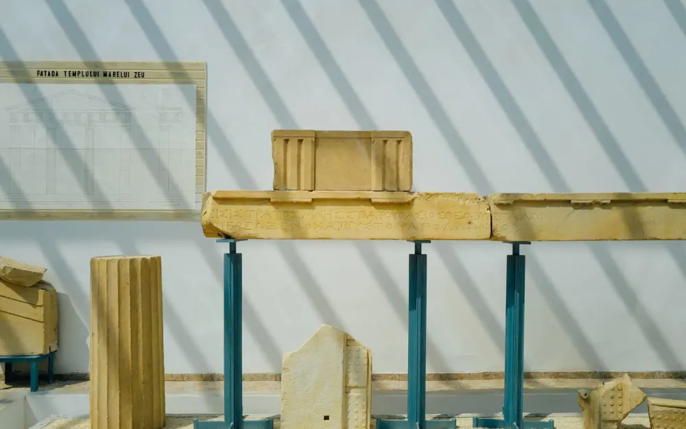 Symbolbild: Ancient Greek architectural fragments displayed in a museum with shadows.