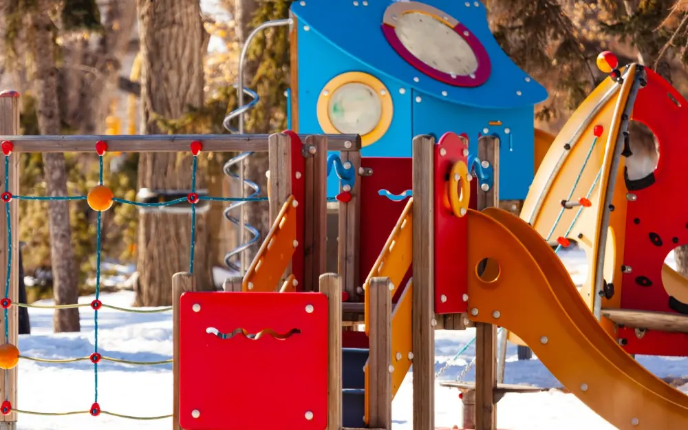 Symbolbild: Bright playground equipment in a snow-covered park during winter.