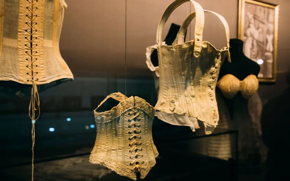 Symbolbild: Showcase with collection of historical corsets with laces near picture on wall on exhibition