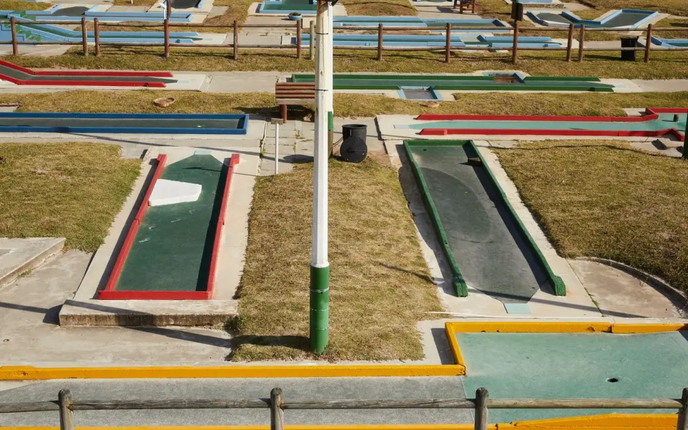 Symbolbild: From above of small dark green tracks for mini gold surrounded by multi colored curbs and lawns in sunlight