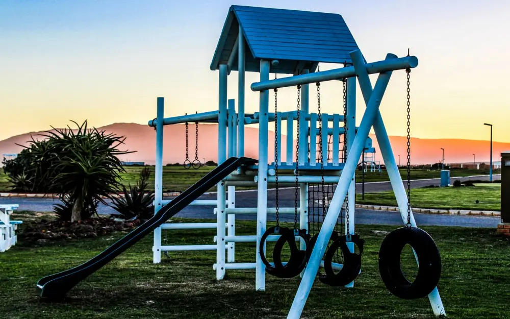 Symbolbild: Outdoor playground with swings and slide captured at sunset, offering a serene view.