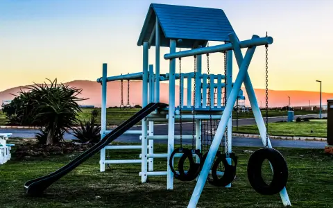 Symbolbild: Outdoor playground with swings and slide captured at sunset, offering a serene view.