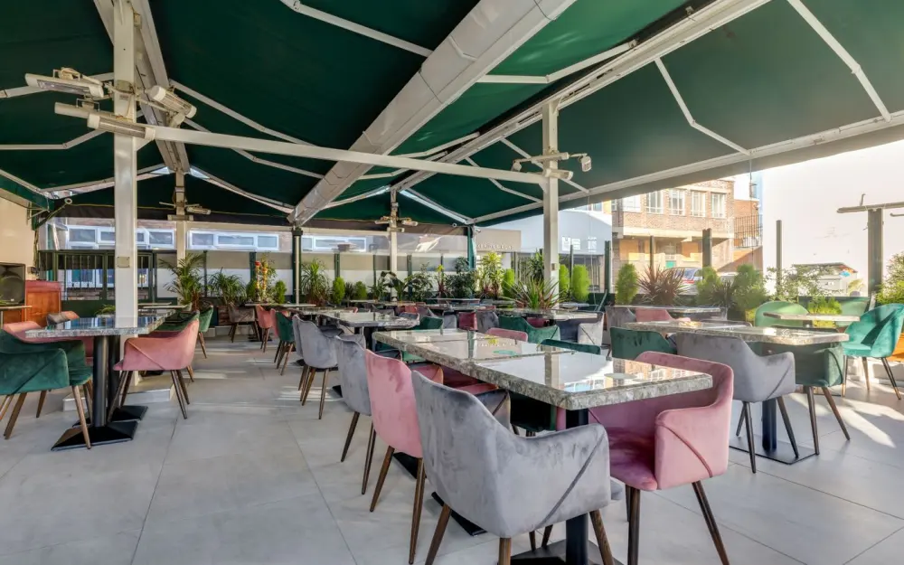 Symbolbild: Spacious terrace café seating with vibrant armchairs and lush plants.