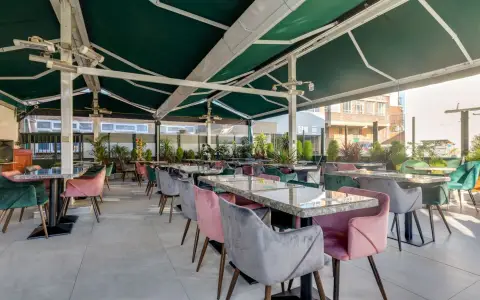 Symbolbild: Spacious terrace café seating with vibrant armchairs and lush plants.