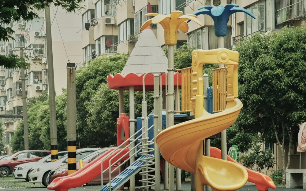 Symbolbild: Vibrant playground with slides and equipment in an urban park setting surrounded by apartment buildings.