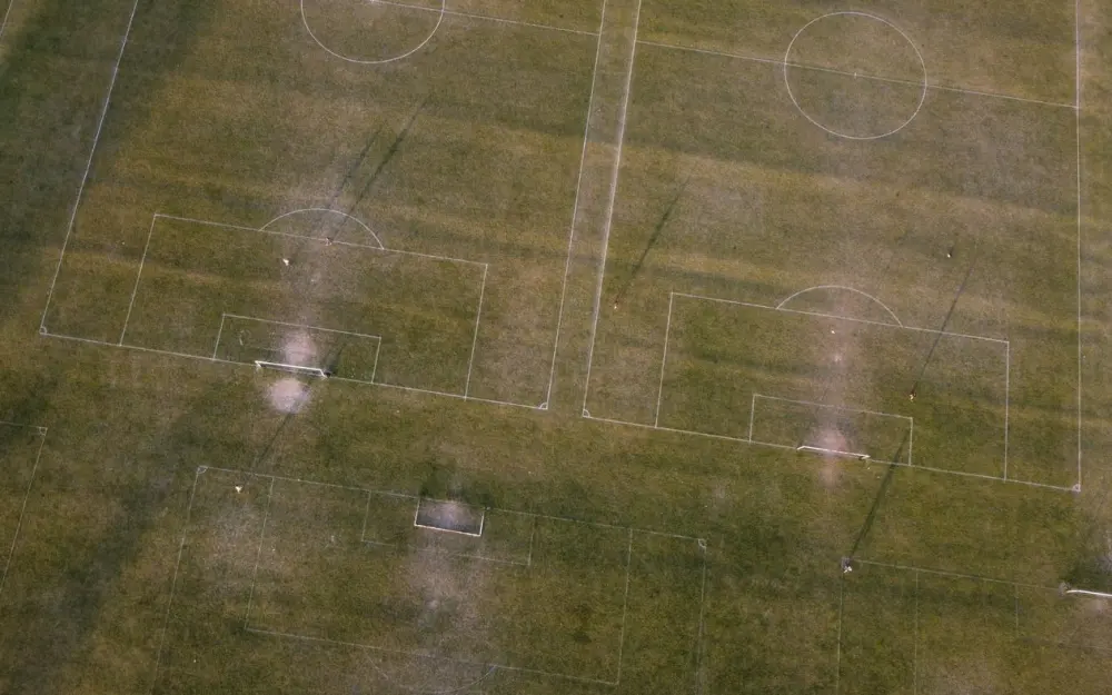 Symbolbild: Aerial shot of soccer fields in Luton, England, showcasing green grass and goalposts.