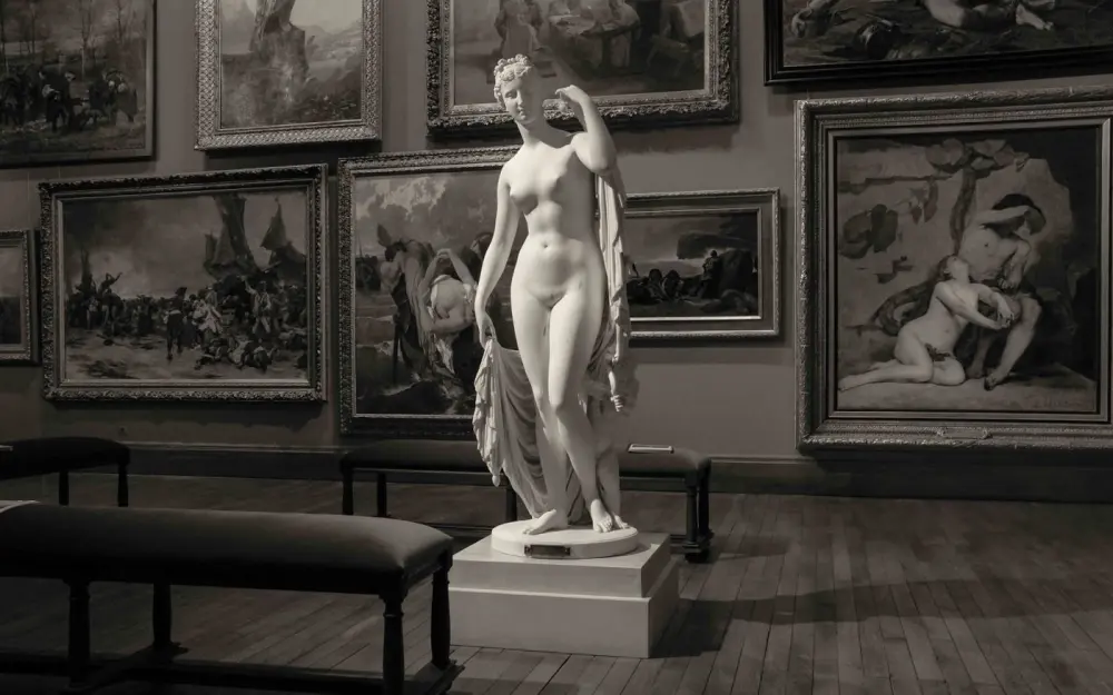 Symbolbild: Grayscale image of a classic sculpture in a French art gallery, emphasizing artistry.