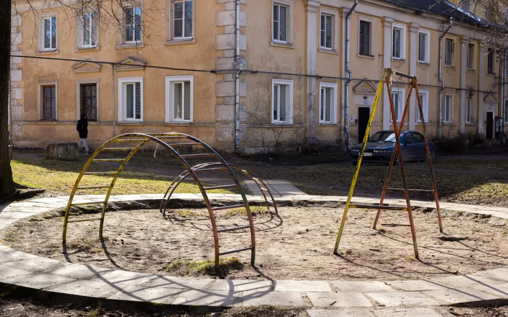 Symbolbild: Old playground with climbing frames in front of a weathered apartment building, urban setting.
