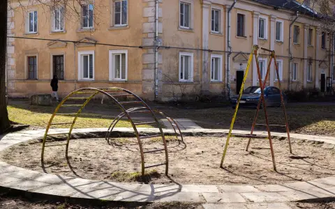 Symbolbild: Old playground with climbing frames in front of a weathered apartment building, urban setting.